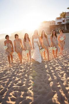 the bride and her bridesmaids walk on the beach at sunset in their dresses