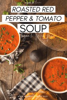 two bowls of roasted red pepper and tomato soup on a wooden table with toasted bread