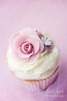 a cupcake with white frosting and pink flowers