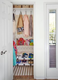 an open closet with shoes and bags hanging on the wall, next to a door