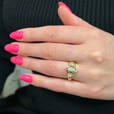 a woman's hand with pink nail polish and a gold ring on her finger