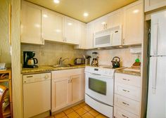 a kitchen with white cabinets and appliances in it