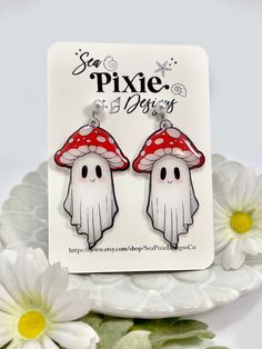 a pair of earrings with mushrooms on them