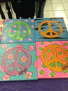 four painted peace signs on top of a purple tablecloth with pink and blue flowers