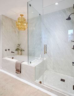 a bathroom with a tub, shower and chandelier