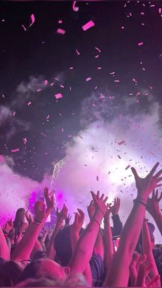 people are throwing confetti in the air at a concert with their hands up