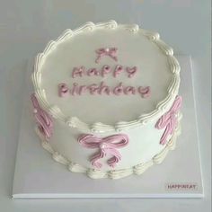 a white birthday cake with pink bows on top and happy birthday written on the side