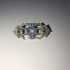 A Ladies Platinum 1 3/4 Inch Long Antique Brooch Set With A 12 Mm Round Natural Blue Grey Star Sapphire Weighing Approximately 10 Carats. The Brooch Is Also Set With 104 Round Diamonds And 6 Marquise Cut Diamonds Having A Combined Weight Of Approximately 1.33 Carats. Sapphire Brooch, Antique Brooches, Star Sapphire, Marquise Cut Diamond, Marquise Cut, Round Diamonds, Bracelet Watch, Blue Grey, Diamond Cuts