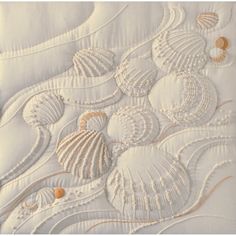 an embroidered piece with seashells on it is shown in white and gold colors