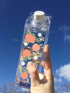 someone is holding up a water bottle with stickers on it and there are trees in the background