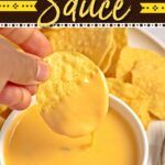 a hand dipping a tortilla chip into a bowl of yellow sauce next to chips