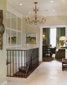 a living room filled with furniture and a chandelier hanging from the ceiling next to a doorway