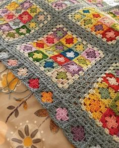 a crocheted blanket is laying on top of a bed with flowers and leaves