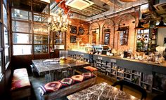 the interior of a restaurant with wooden tables and chairs, chandeliers hanging from the ceiling