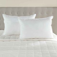 two white pillows sitting on top of a bed