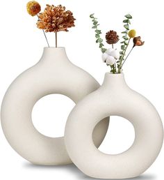 two white vases with flowers in them sitting side by side on a white surface