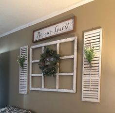 three shutters are hung on the wall above a bed with a wreath and greenery