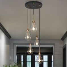 three light bulbs hanging from the ceiling above a table with chairs and potted plants