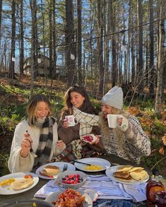 three women sitting at a picnic table with food