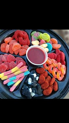 a black tray filled with different types of candy and candies next to a cup of liquid