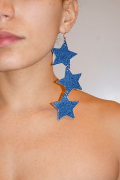 a close up of a person wearing large earrings with stars on the back of them