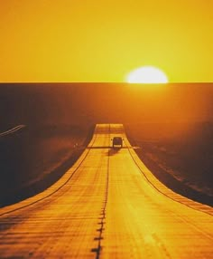 the sun is setting over an empty road in the middle of nowhere, with a car driving on it