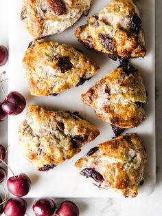 fresh cherry scones are arranged on a white platter next to some cherries