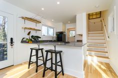 two stools are in front of the kitchen counter and stairs leading up to the second floor