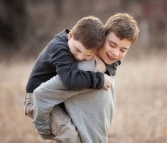 two young boys hugging each other in a field