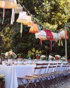 a long table with many chairs and tables covered in paper lanterns hanging from the ceiling