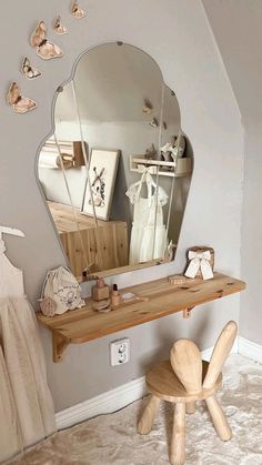 a mirror sitting on top of a wooden table next to a stool and wall hangings