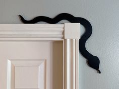 a door handle on the side of a white door with a black cat's tail sticking out of it