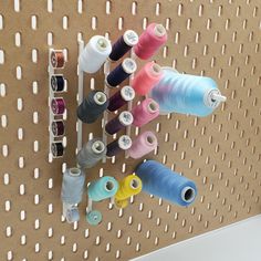 several spools of thread are hanging on a pegboard