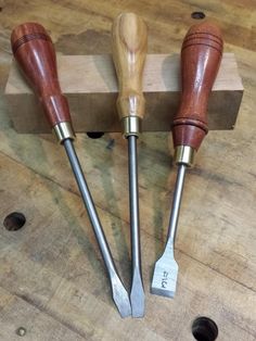 three woodworking tools sitting on top of a wooden table