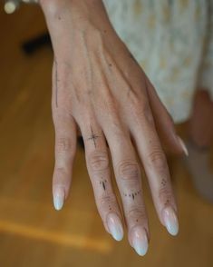 a woman's hand with cross tattoos on her left thumb and fingernails