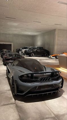 a bunch of cars are parked in a room with concrete flooring and white walls