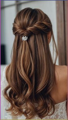 a woman with long brown hair wearing a half - up braid and a flower clip in her hair