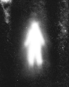 a black and white image of a person standing in the dark