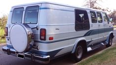 an old white van parked on the side of the road with a surfboard strapped to it's door