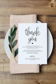 a white plate topped with a napkin next to a green leafy place card on top of a wooden table