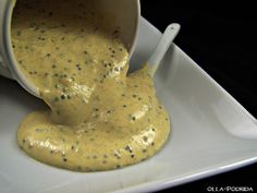 a white bowl filled with yellow sauce on top of a white plate