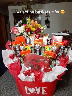 a valentine's day gift basket with chocolates, candy and flowers in it