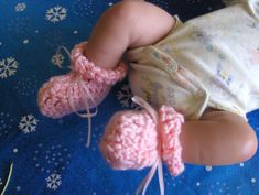 a baby laying on top of a blue blanket wearing pink crocheted booties