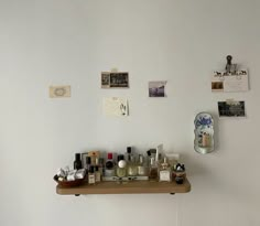 a wooden shelf with bottles on it in front of a wall filled with magnets