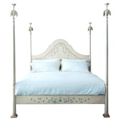 a white bed with blue sheets and pillows on it's headboard, in front of a white background