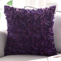 a white couch with a purple flowered pillow on it's back and side