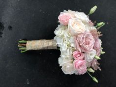 a bridal bouquet with pink and white flowers on a black surface, top view