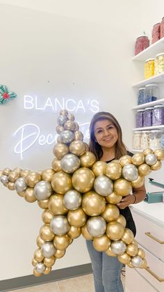 a woman holding up a star shaped balloon in front of a store sign that reads, blancca's decor