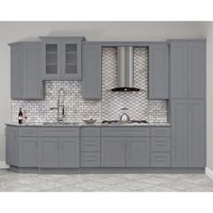 a kitchen with gray cabinets and white tile backsplash