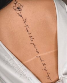 the back of a woman's neck with a flower tattoo on her left side